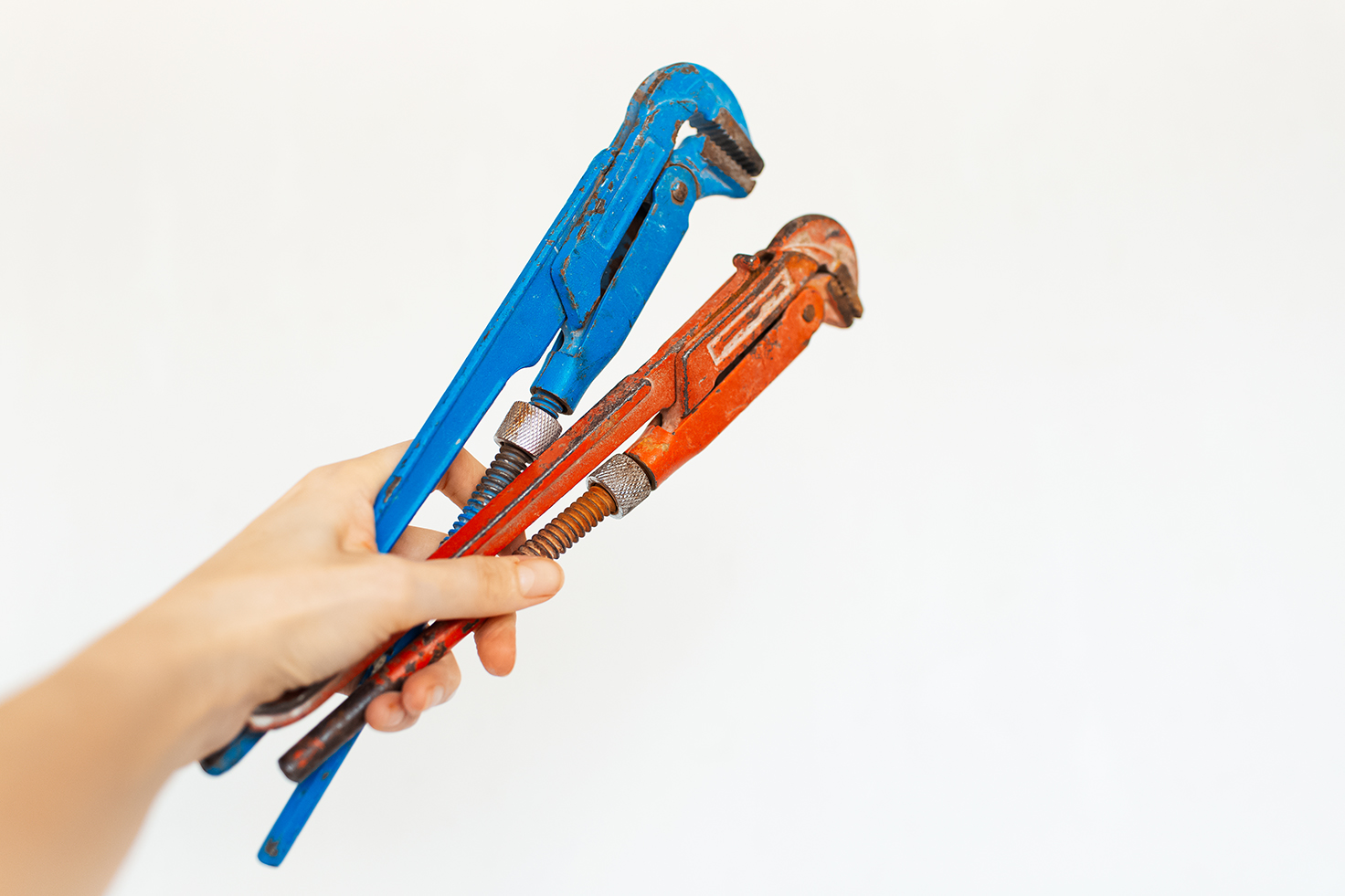 Close-up of adjustable gas wrenches in hand on white background.